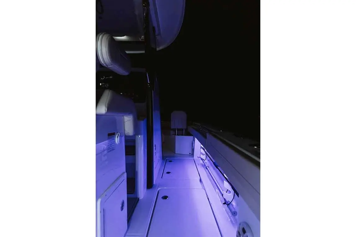 Illuminated interior of a boat showcasing white seating and blue ambient lighting against a dark background.